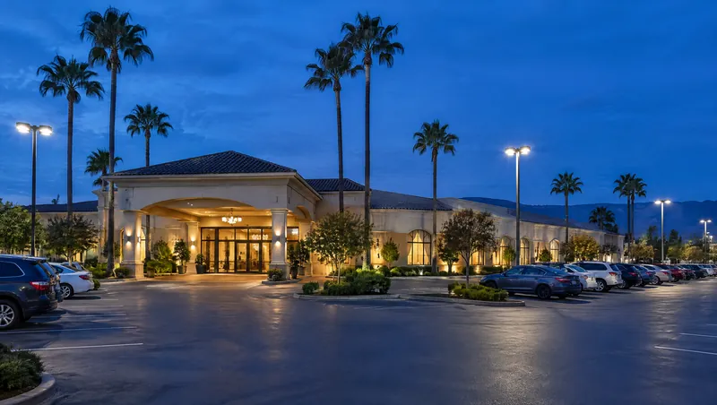 Mặt tiền Ngọc Bích Palace lúc chạng vạng, cửa vào sáng đèn, hàng cọ và bãi đậu xe rộng phía trước