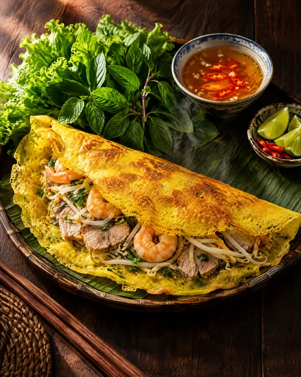 Bánh xèo vàng giòn gấp đôi trên lá chuối, rau sống và nước mắm