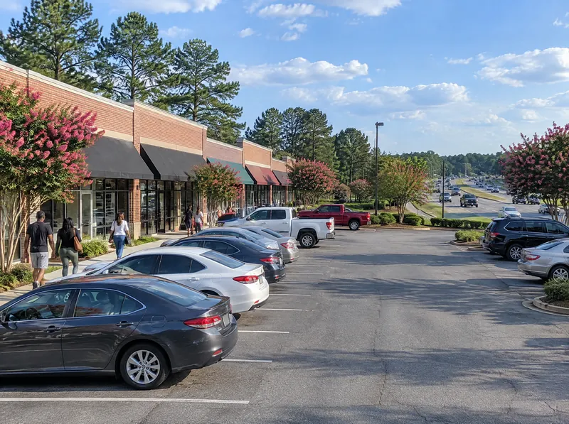 Dãy cửa hàng trên Buford Highway vào buổi chiều, bãi xe phía trước có vài chiếc ô tô.